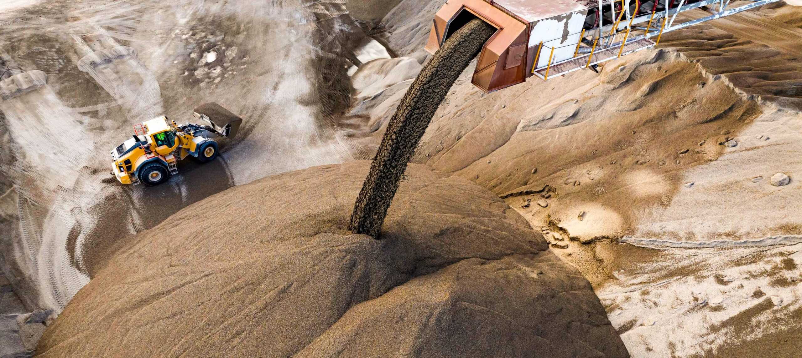 Aerial shot of loader next to pile of product with elevator auger unloading minerals to pile.