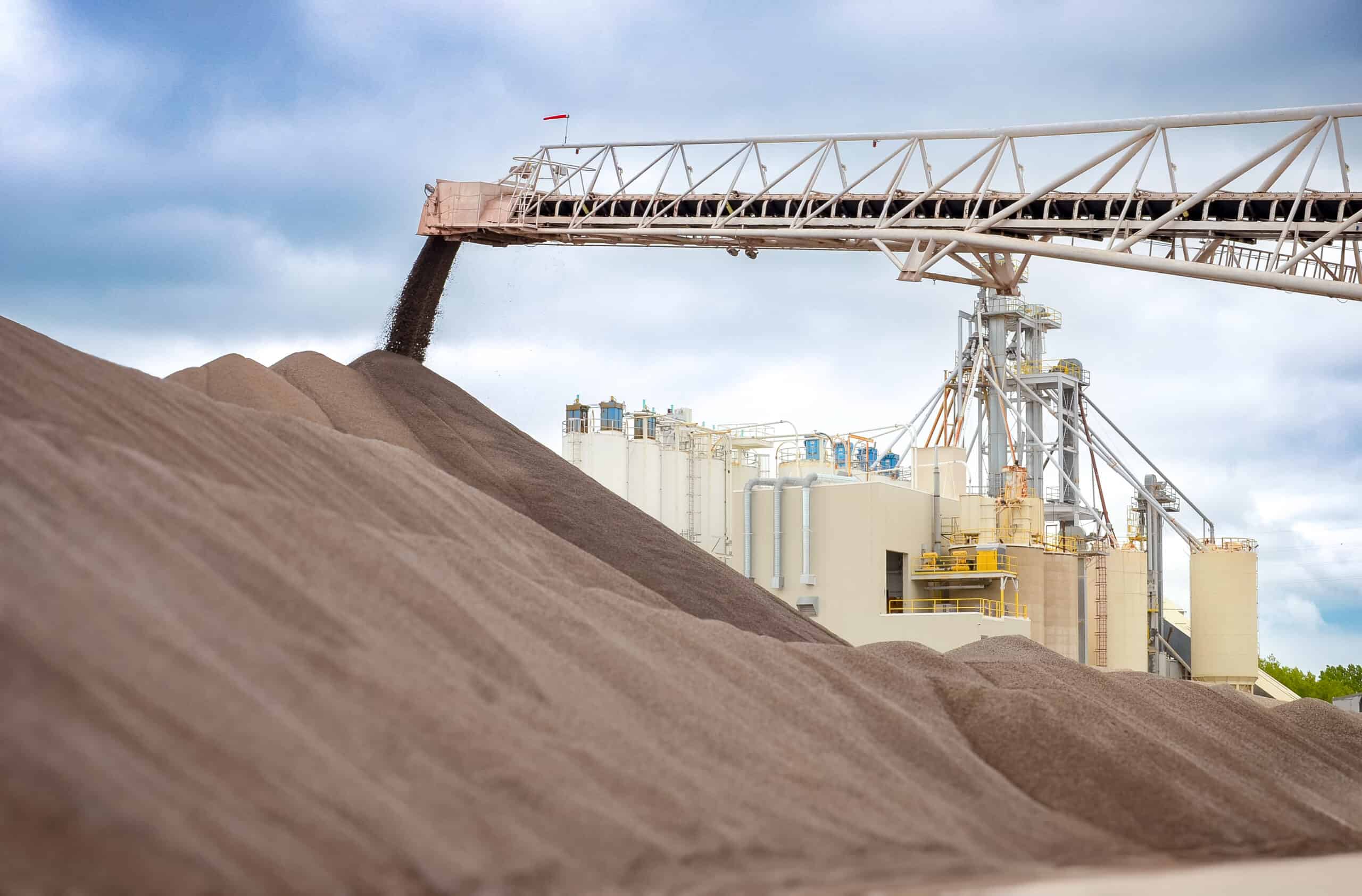 An elevator auger transferring minerals to large pile at a processing plant.