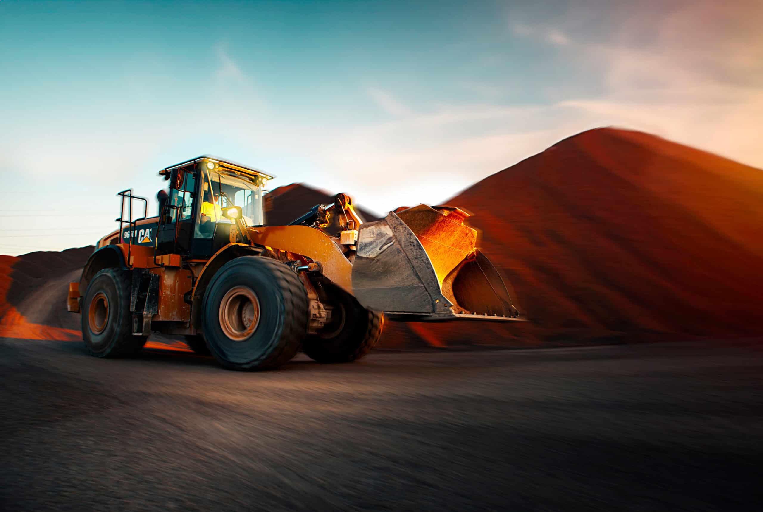 Payloader loading calcium mineral stockpile at mining site during sunset