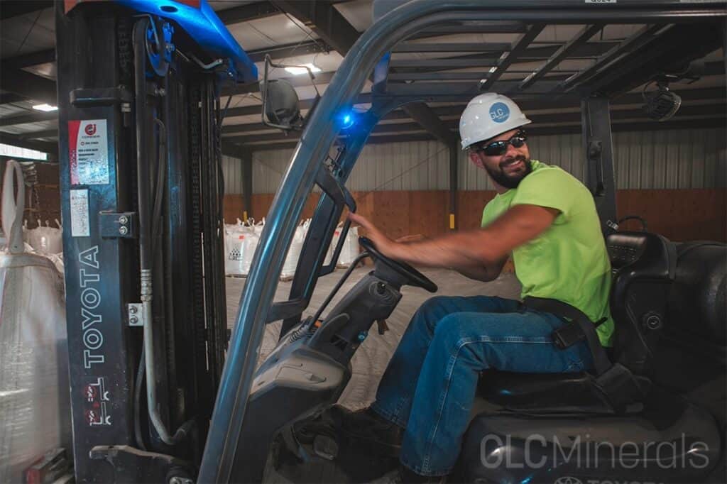 GLC Minerals forklift operator wearing a hard hat and safety glasses while working in the warehouse.