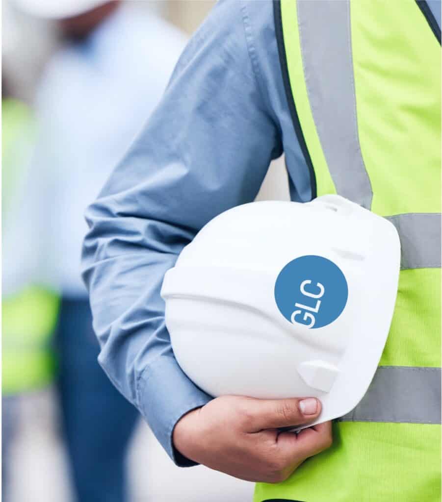 GLC Minerals hard hat held by a worker wearing a high-visibility safety vest.